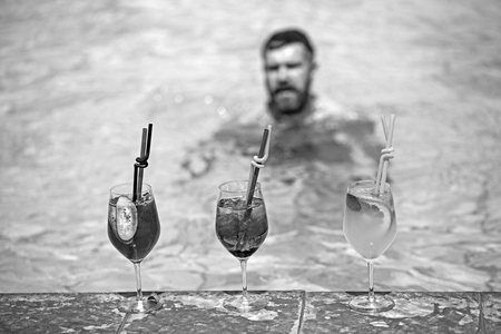 man drinking cocktails at luxurious swimming pool in hotel, relaxation and tourism.の写真素材