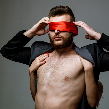 Blindfolded. Woman covering man eyes. Sexy girl closes eyes of a man.の写真素材