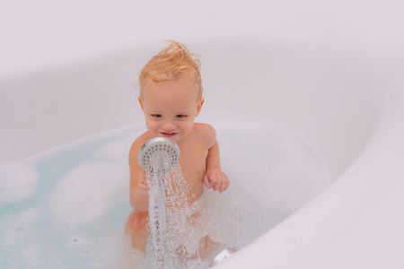 Portrait of smiling kid. Beautiful little boy having bubble bath. Playing in tub. Little child bathing in soapsuds. Baby bath. Kids playing in tub.の写真素材