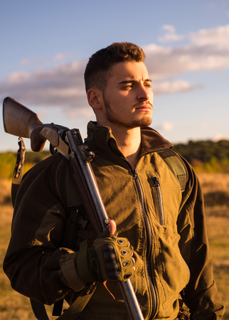 Close up Portrait of hamdsome Hunter. Hunter with shotgun gun on hunt. Hunter aiming rifle in...