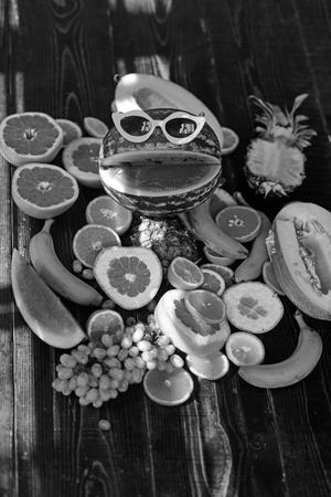 Watermelon in funny sunglasses with smile. Fresh fruits still life on wooden table. Vegetarian food for detox diet and health. Vitamin dieting and nutrition. Summer vacation concept.の写真素材