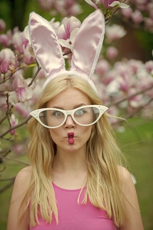 easter, funny woman in glasses and bunny ears at spring magnolia flower.