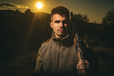Hunting Gear - Hunting Supplies and Equipment. Hunter with shotgun gun on hunt. Illegal Hunting Poacher in the Forest. Close up Portrait of hamdsome Hunter.の写真素材