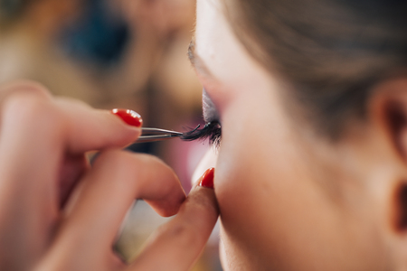 Female beauty visage concept. Pretty woman with perfect makeup. A professional make-up artist paints eyelashes models in the studio.の写真素材