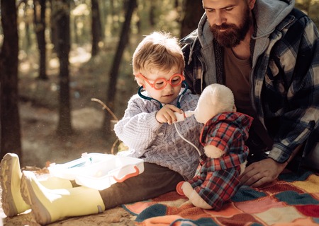 Cute boy with nose wiper near autumn tree. Father and child son in autumn park having fun and...
