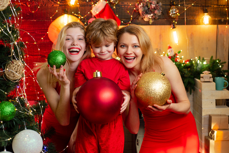 Excited woman and lovely little boy with Christmas decoration are standing by the Christmas tree.Family time. New Year Party mood.の写真素材