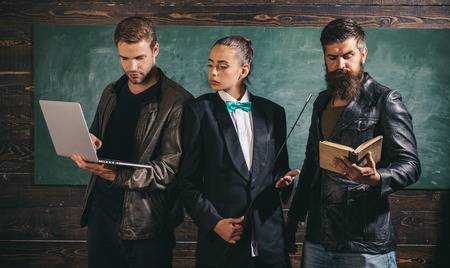 School teachers. Bearded man masculine girl and handsome guy school colleagues. Teaching and education occupation. Diversity concept. School staff. People with laptop book stand in school classroomの写真素材