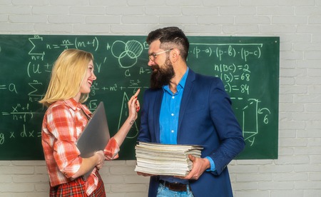 Bearded tutor helping his student. Teacher couple. Teacher helping his students with math or mathematics on education class.の写真素材