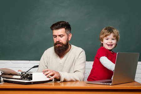 Young adult concept. Elementary school kid and teacher in classroom at school. School children. Chalkboard background. Man teacher play with preschooler child.の写真素材