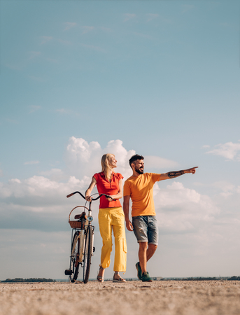 The concept of love and lifestyle. Sexy woman with vintage bike in a country road. Adventure and vacations concept. Smiling couple having fun over sky background.の写真素材