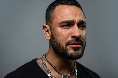 Crying wont help. Lonely single man. Hispanic guy feeling lonely and melancholy. Lonely man suffering from depression. Unhappy latino man crying over lonely lifeの写真素材