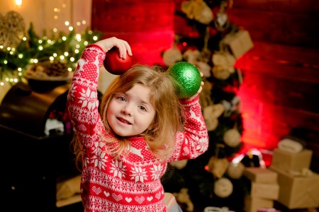 Merry christmas and happy new year. Cute little child girl play ornaments balls christmas tree. Kid enjoy winter holiday at home. Home filled joy. Cozy christmas atmosphere. Girl baby christmas eveの写真素材