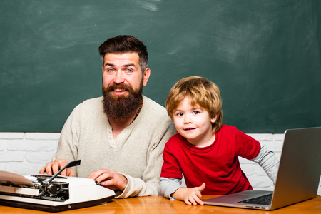 Young or adult. Happy family. Child learning. Preschool pupil. Man teacher play with preschooler child. Teacher and schoolboy using laptop in class.の写真素材