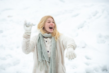 Young american woman throwing snowball at sunny day in the winter park. Girl playing with snow in park in America. Women woman. Winter emotion.の写真素材