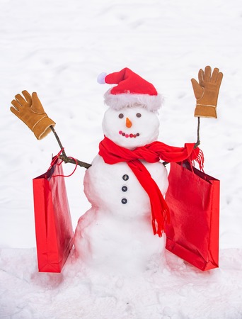 Cute snowman at a snowy village. Greeting snowman. Handmade snowman in the snow outdoor. Snowman gentleman in winter hat.の写真素材
