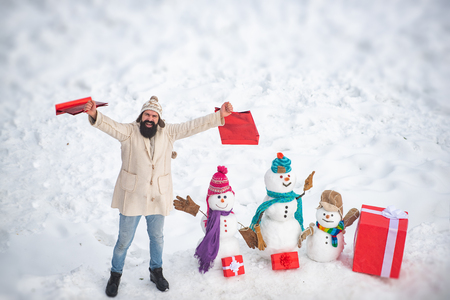 Mother snow-woman, father snow-man and kid wishes merry Christmas and Happy New Year. Happy snow man and bearded man on sunny winter day.の写真素材