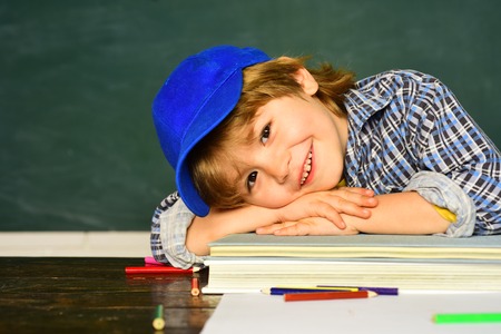Cute little preschool kid boy in a classroom. Schoolchild. Happy mood smiling broadly in school. Schoolboy. Elementary school and education. First school day.の写真素材