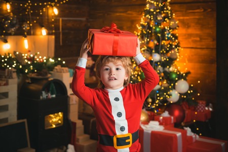 Childhood moments. Christmas stocking concept. Child cheerful face got gift in christmas sock. Contents of christmas stocking. Oh happy day. Joy and happiness. Kid boy santa hold christmas giftの写真素材