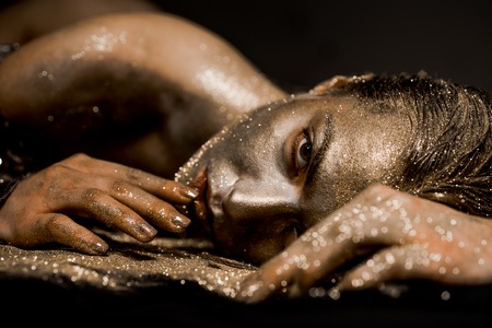 Pure gold. Golden lady relaxing. Vogue and glamour concept. Golden skin. Sexy girl face makeup body art metallized color - Gold concept. Golden skin. Golden mask. Luxury beauty procedureの写真素材