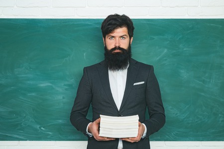 Preparing for exam in college. Teacher preparing for university exams. Good teachers enjoy teaching. Young teacher near chalkboard in school classroom.の写真素材