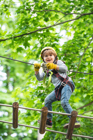 Child boy having fun at adventure park. Go Ape Adventure. Cargo net climbing and hanging log. Early childhood development. Artworks depict games at eco resort which includes flying fox or spider net.の写真素材