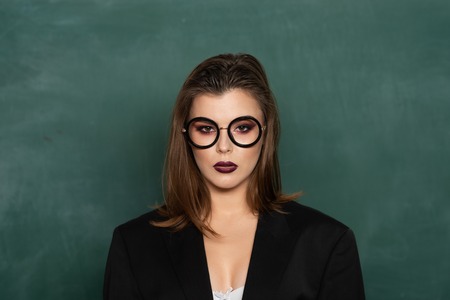Teenage students with school books. Blonde sexy woman in front of chalkboard. Ready for study. Sensual female student with books. Portrait of an college sexy student girl on campusの写真素材