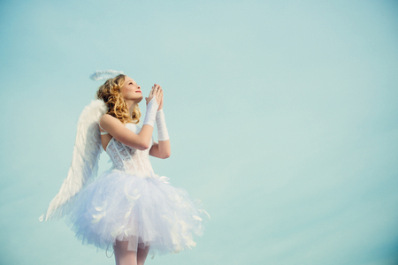 A beautiful teen with blonde curly hair as cupid - Valentines Day. Valentines day. Little angel in love. Girl angel with halo in white angel dress.の写真素材