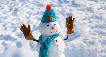 Happy new year. Christmas background with snowman. Happy funny snowman in the snow. Handmade snowman in the snow outdoor. Snowman on a background snow-covered fir branches.の写真素材