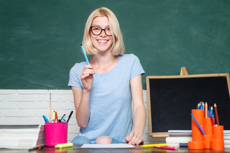 Young woman sitting at table doing assignments library. Portrait of college student in college. Female student taking notes from a book in college.の写真素材