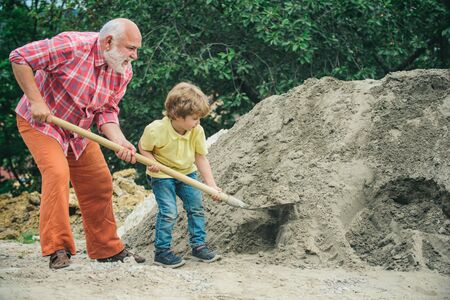 Grandfather with his grandson hard working. Little grandson helping his grandfather with building work. Child and works. Help for grandpa.の写真素材