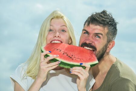 Watermelon as a symbol of summer, unity and oneness. Portrait of happy couple enjoying watermelon on summer holiday, having fun together.の写真素材