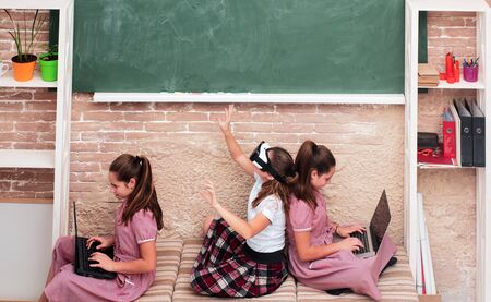 Children in the school space with gadgets sitting on the floor. Education, modern school, learning,...