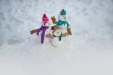 Merry Christmas and happy new year greeting card. Happy snowman couple and snowman child standing in winter Christmas landscape. Holiday poster design.の写真素材
