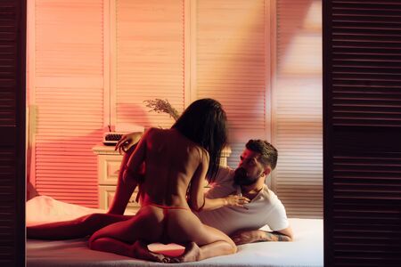 Tempting and seductive. Seductive woman seducting man in bed. Sexy woman in seductive lingerie using seduction tactics in bedroom. Sexi woman with seductive look infront of bearded manの写真素材
