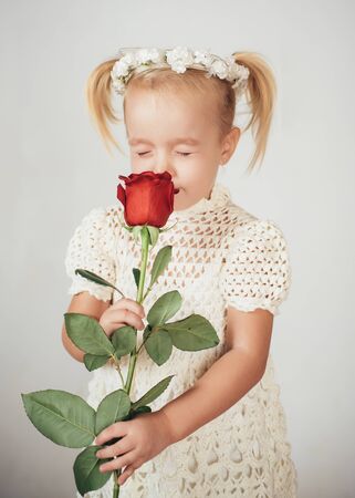 love present. childrens day. small kid with red rose. happy childhood. valentines day. romantic date. little girl in vintage dress. Beauty. retro style. happy birthday. wedding. what great a smellの写真素材