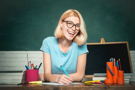 Teacher is skilled leader. Young teacher in glasses over green chalkboard background. Beautiful teacher in classroom. Student studying in the classroom. World teachers day.の写真素材