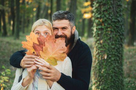 Autumn outdoor portrait of beautiful happy girl and bearded man walking in park or forest. Fashion autumn portrait woman and man with yellow maple leaves on nature background.の写真素材