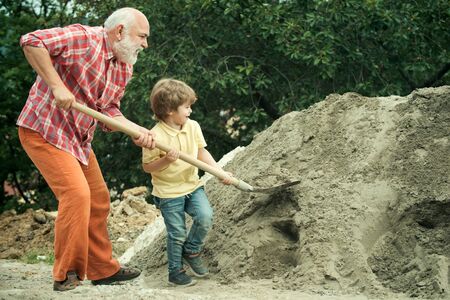 Little son helping his father with building work. Childhood concept. Future worker son with father. Child and works. Little son worker with shovel.の写真素材