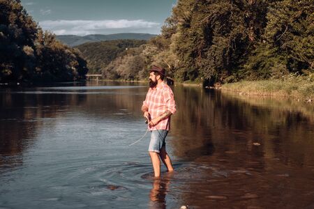 Fisher man fishing with spinning reel. Fly rod and reel with a brown trout from a stream. Fishing in river.の写真素材