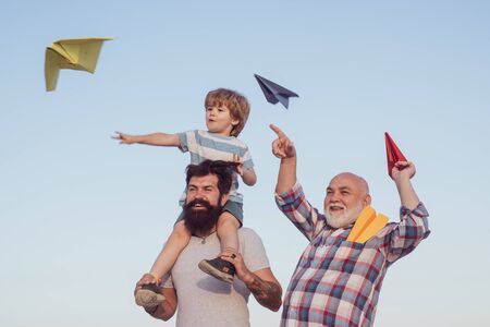 Happy fathers day. Happy grandfather father and grandson with toy paper airplane over blue sky and...