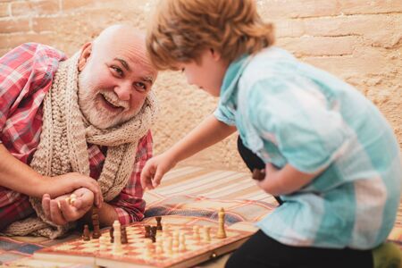 Granddad with grandson on a playing chess.の写真素材