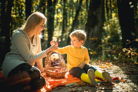 Teaching son healthy nutrition. Having snack picnic hike. Happy childhood. Mom and kid boy relaxing while hiking forest. Family picnic. Mother pretty woman and little son relaxing forest picnicの写真素材