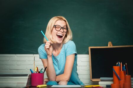 Student. Young teacher in glasses over green chalkboard background. School student. Portrait of a female student in university.の写真素材