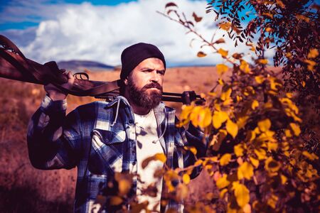 Hunter with shotgun gun on hunt. Autumn hunting season. Autunm hunting. Hunting Licenses. Bearded hunter man holding gun and walking in forest.の写真素材