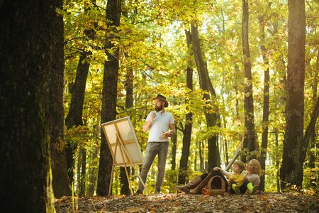 Hobby concept. Painting in nature. Start new picture. Beauty of nature. Bearded man woman and cute son relaxing autumn nature. Drawing from life. Painter artist with family relaxing in forestの写真素材