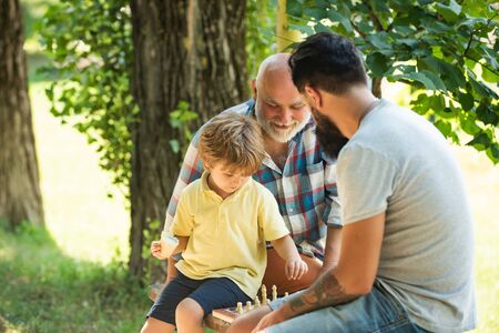 Grandfather and grandson playing chess. Dad and Grandpa with his child son are playing Chess. Senior...