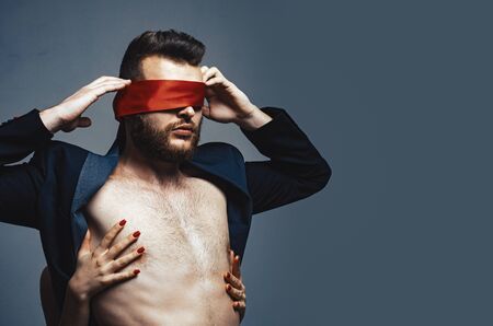 Blindfolded. Sexy girl closes eyes of a man. Woman covering man eyes.の写真素材