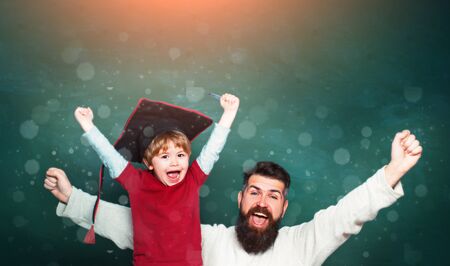 Father teaching her son in classroom at school. Two generations. Young boy doing his school homework with his father. Future dream and people concept. Blackboard for copy space text.の写真素材