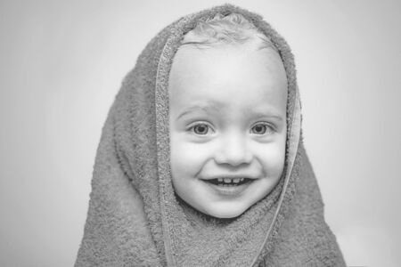 Smiling baby bathing under a shower at home. Little baby washing with a bubbles in bath in a hat. Happy bath time.の写真素材