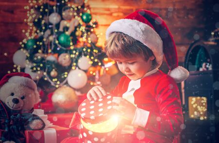 Santa boy little child celebrate christmas at home. Lovely baby enjoy christmas. Family holiday. Boy cute child cheerful mood play near christmas tree. Merry and bright christmasの写真素材